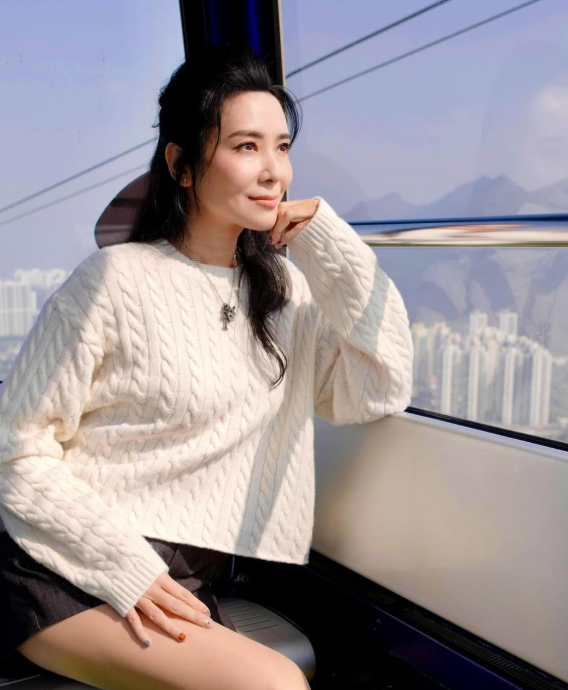 郭羨妮身穿白色麻花冷衫坐纜車，展示50歲逆齡緊緻肌膚與抗衰老保養成果。