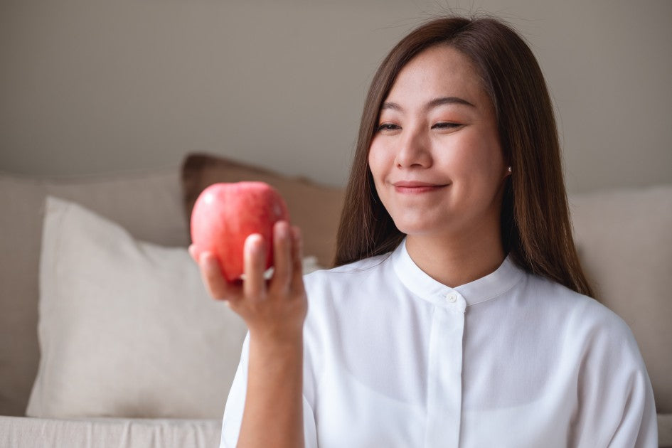 年輕女士手持紅蘋果微笑，示範三日蘋果斷食法瘦身技巧及了解去水腫減肥原理。