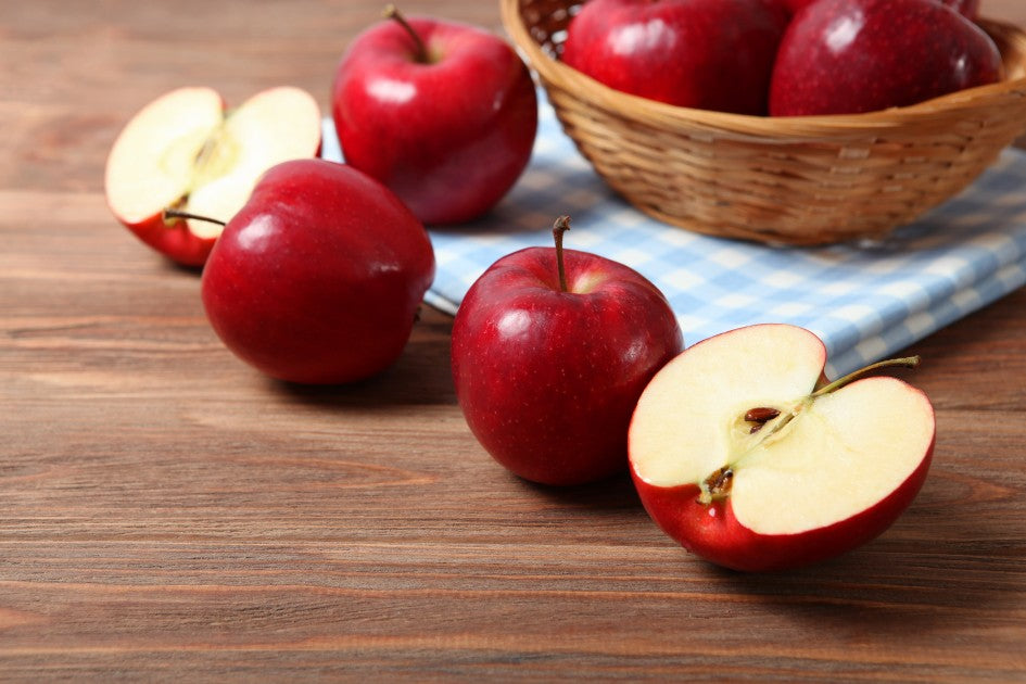 Beauty100-magazine 探討蘋果斷食法瘦身原理，木質桌面擺放新鮮完整紅蘋果與切片。